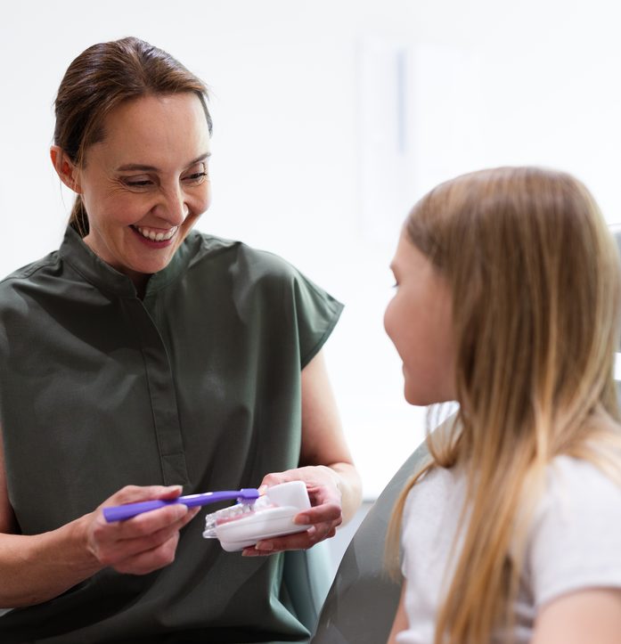 Dentist showing a child how to brush teeth at Everwell Dental